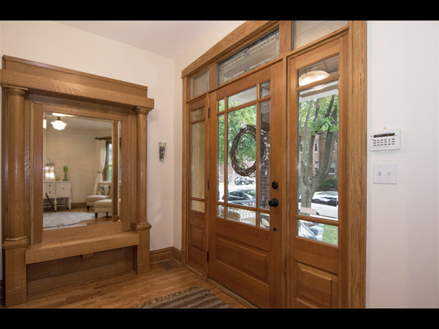Entryway with wooden doors, sidelight windows, and mirror showing interior home entrance