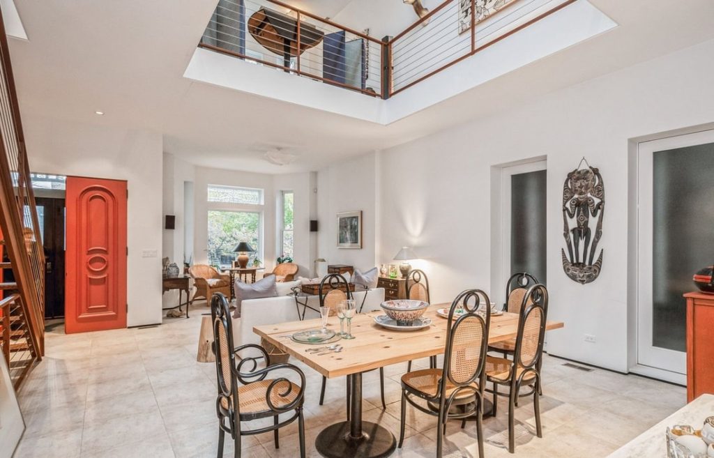 Modern dining room with wooden table, metal chairs, skylight, and red accent door