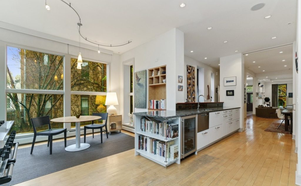 Modern open-concept kitchen and dining area with white cabinetry, black countertops, and natural wood flooring
