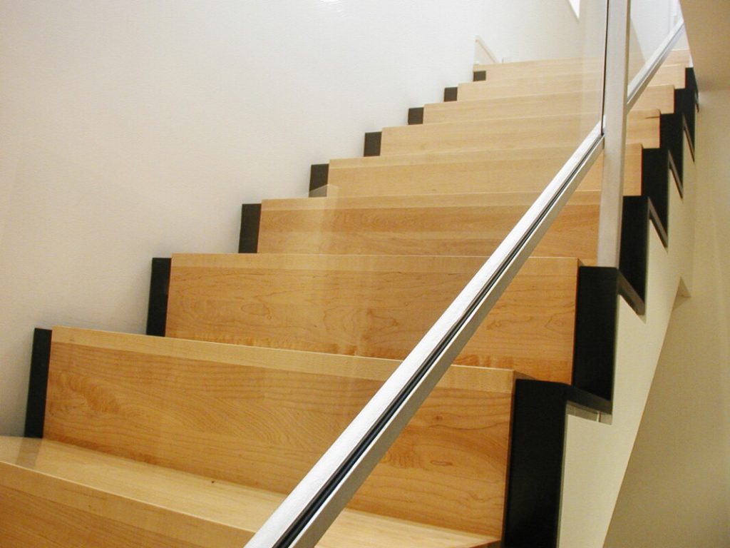 Wooden staircase with metal handrail and black stair nosing strips