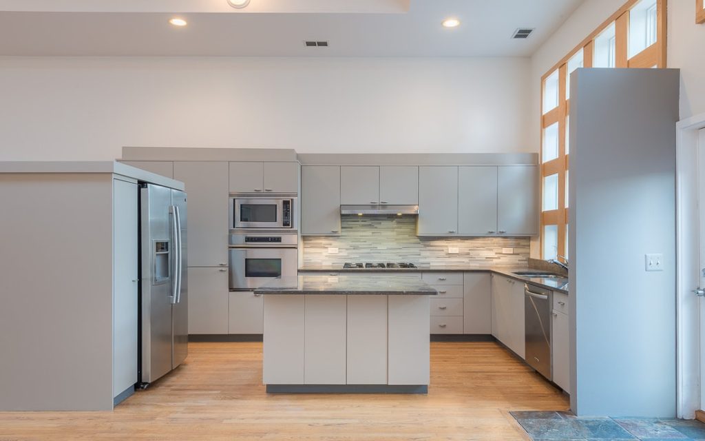 Modern kitchen with white cabinets, stainless steel appliances, island, and wood flooring