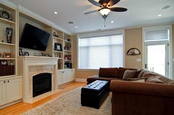 Modern living room with brown sectional sofa, fireplace, built-in shelving, and flat-screen TV